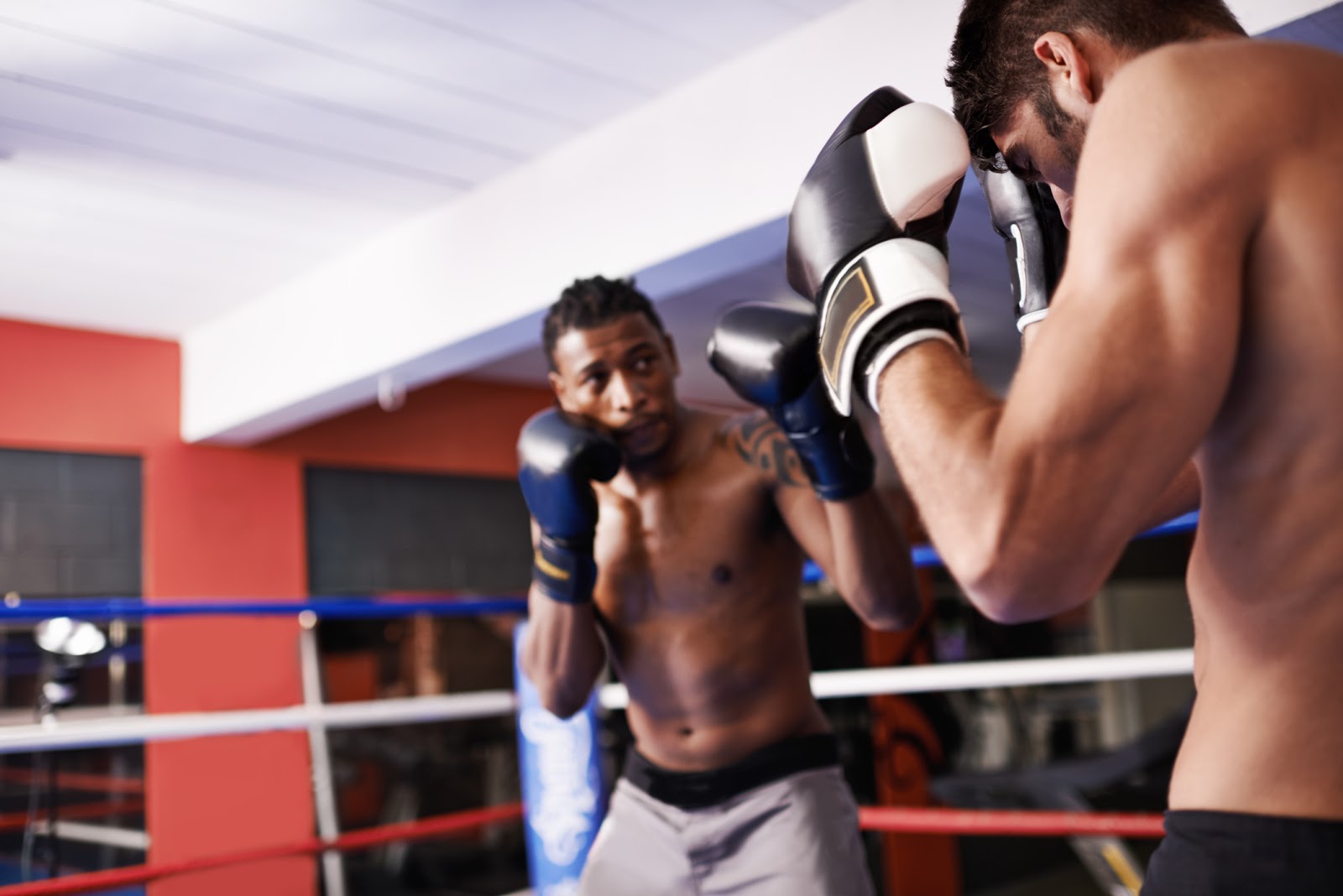 2 men with different boxing styles training in a boxing ring.